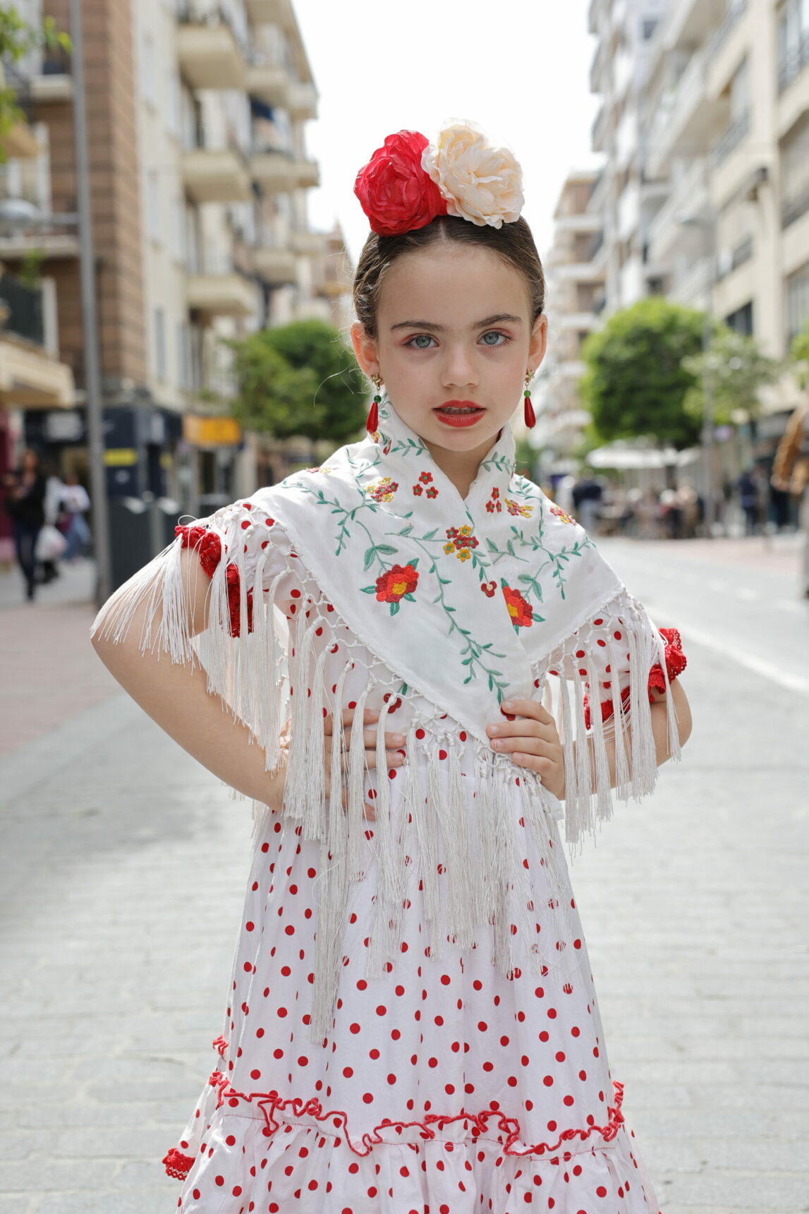 El mantoncillo de niña blanco flores rojas es un básico del look flamenca que puedes combinar con todo tipo de trajes.