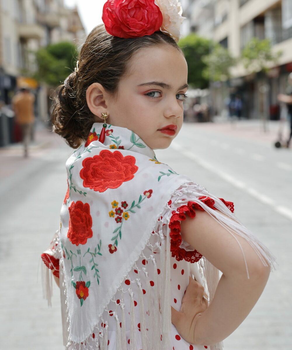 El mantoncillo de niña blanco flores rojas es un básico del look flamenca que puedes combinar con todo tipo de trajes.