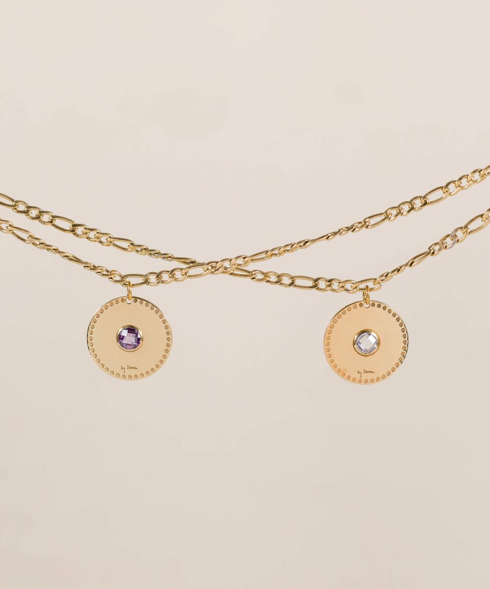 La cadena París es el diseño todoterreno perfecto para lucirlo en tu día a día. Una joya compuesta por una cadena de eslabones asimétricos en color dorado y un charm de medalla circular con una circonita de color en el centro de la medalla. Los charms se pueden intercambiar.