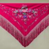 El mantoncillo bordado en crespón fucsia es un básico, puedes combinar nuestro mantón bordado con varios colores de vestido y flores de flamenca.