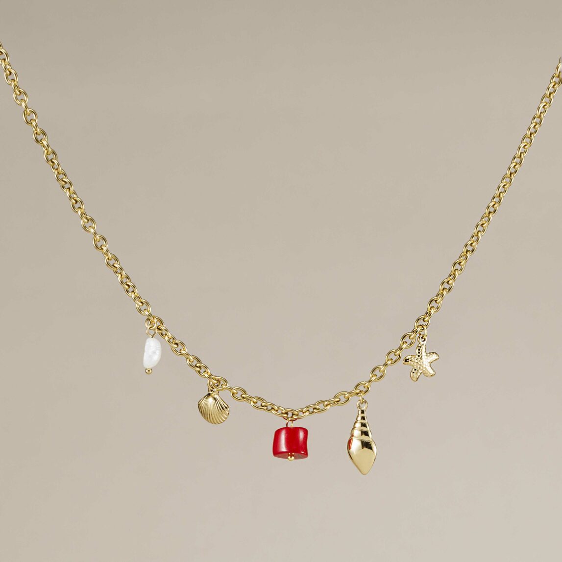 El Collar Formentera es una cadena dorada waterproof con coral rojo, perla y charms marinos. El complemento ideal para tus looks de verano 2025.