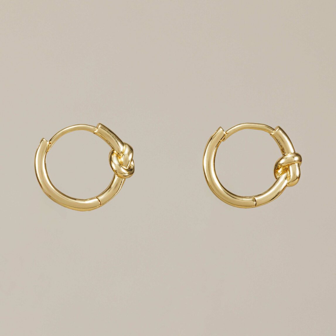 Pendientes aro Nudos con diseño de nudo central, hipoalergénicos y resistentes al agua. Un básico minimalista y versátil en dorado o plateado.